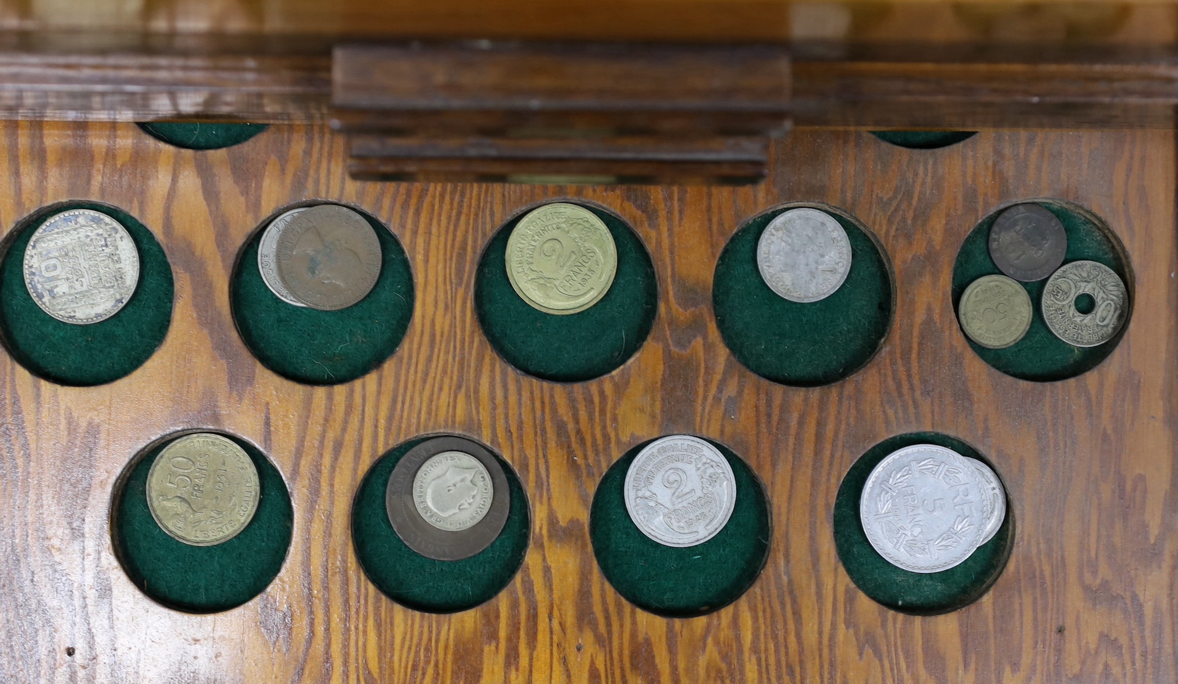 A collection of mixed coinage in a collectors cabinet, 27cm tall